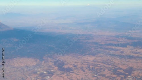 Flying airplane over Mexico clouds sky vlcanoes mountains desert landscape. photo