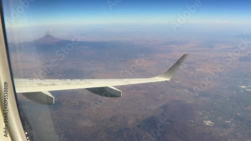 Flying airplane over Mexico clouds sky vlcanoes mountains city desert. photo