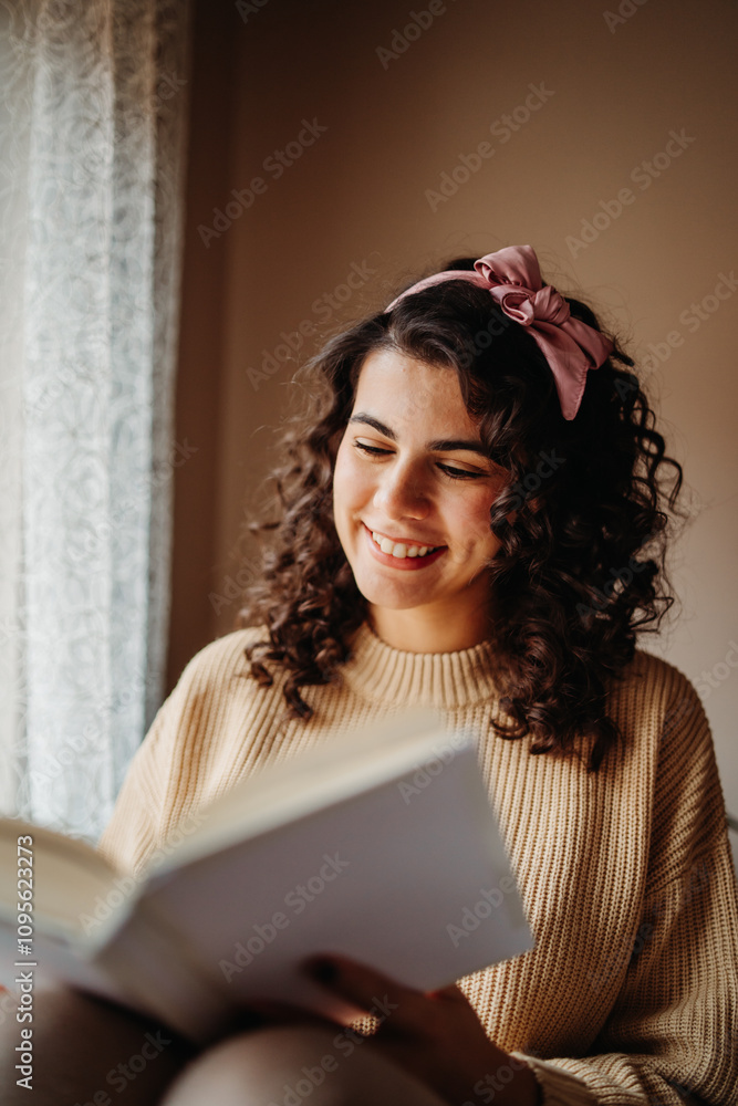 Young caucasian woman reading book or learning by the window Young caucasian woman reading book or learning by the window