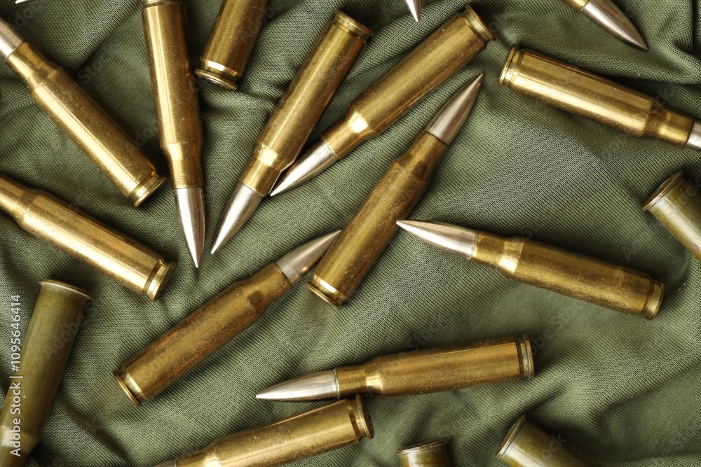 Many rifle bullets on military camo green fabric background Many rifle bullets on military camo green fabric background