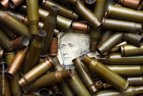 Conceptual image of US presidents face surrounded by many used rifle cartridges. Details of US currency bill through pile of used ammo shells photo