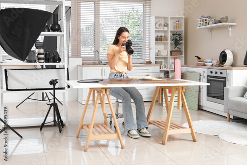 Young female photographer taking picture of dessert in kitchen