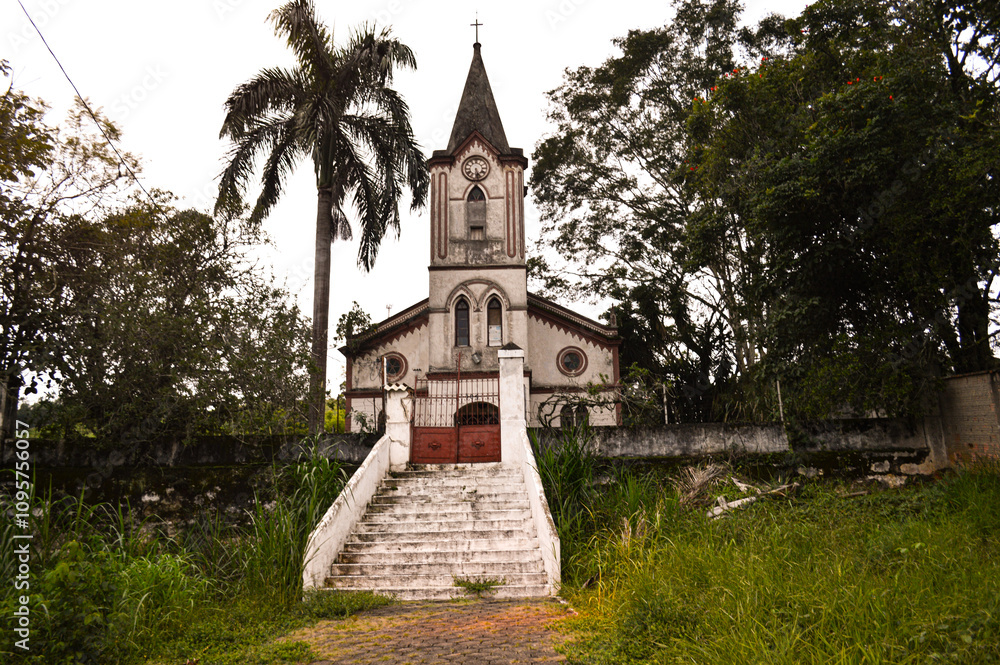 Naklejka premium The historic Senzala Chapel in Lavrinhas, São Paulo, set against lush green surroundings. This rustic chapel is a cultural and architectural symbol, blending tradition with serene landscapes.