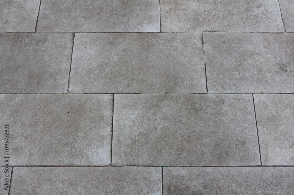 Naklejka premium Texture of square paving tile. Pattern of tiles in the street. Close up of gray concrete pavers background.