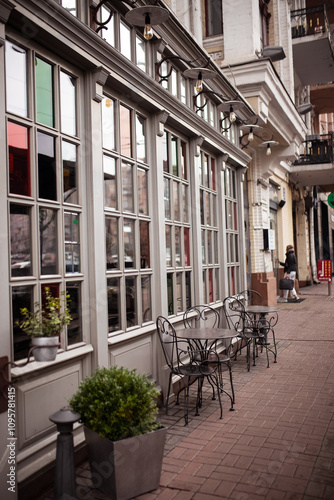 фотографія A charming english cafe with wicker chairs and tables set out on a cobblestone sidewalk on a drizzly day