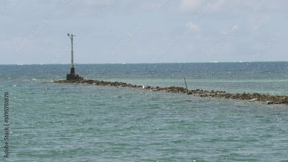 Narrow strip of rocks and corals with a pole at sea Narrow strip of rocks and corals with a pole at sea