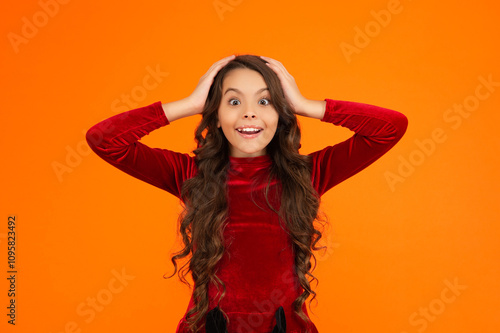 Portrait of teen girl with curly hair. Girl with surprised face isolated on orange. What a surprise. Teen girl portrait with curly hair. Girl teenager showing emotions. Wow curly hair