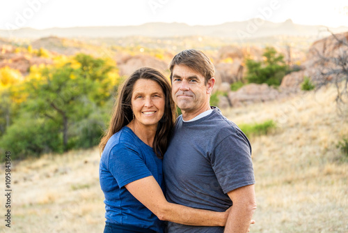 Couple embraces in a serene outdoor setting during golden hour near rocky landscape