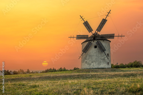 Windmill with wooden wings in a landscape setting. Fields, meadows and flowers appear in the sunset. Landscape shot in nature with a mill. historically untypical for the Balaton region in Hungary