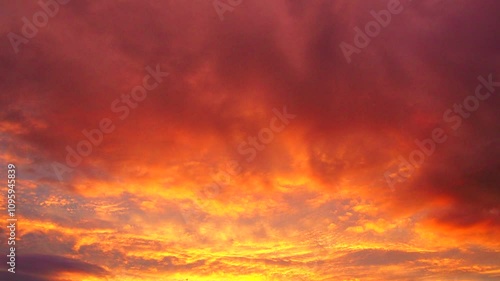 Yellow orange red sunset sky clouds. Soft warm hue of yellow and red casts serene and beautiful atmosphere. Gentle rays of setting sun paint horizon. Dramatic sunset. Real time, cumulus clouds