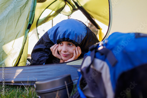 Konstfotografi happy smiling child lies in a tent covered with a sleeping bag