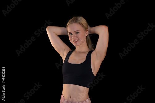 Smiling Athletic Girl in Black Sports Bra Posing Against Black Background