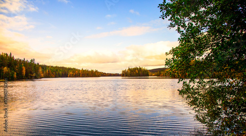 Fototapeta Naklejka Na Ścianę i Meble -  Sunrise at lake Gränsjön in Swedish municipality Arvika in Värmland important part of Göta river main catchment area. With border of forests in autumn colors and warm colored cloud sky