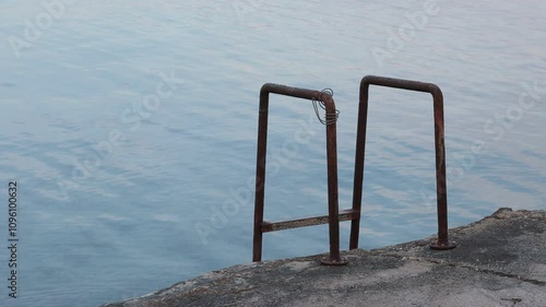 Metal stairs or ladder to enter the water on a pier at privlaka bay, croatia. Tranquil empty setting with sea water in early autumn photo