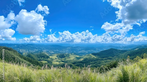 Breathtaking panoramic landscape featuring lush green hills under a bright blue sky filled with fluffy white clouds.