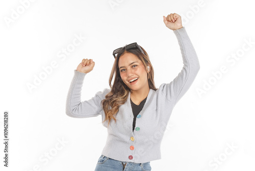 Young Asian woman wearing airpods and glasses enjoying music while dancing raising both hands