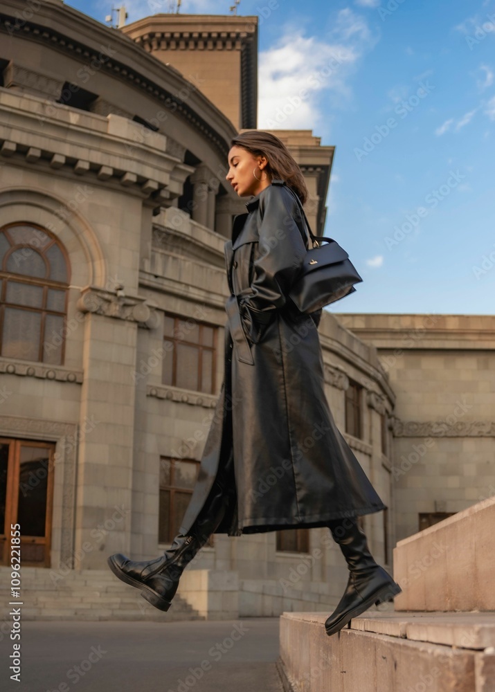 Fototapeta premium Fashionable woman in black leather coat by historic building.