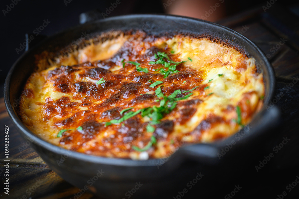 Baked lasagna with cheese and green herbs served in the cast iron skillet Baked lasagna with cheese and green herbs served in the cast iron skillet