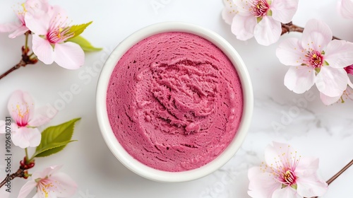 Pink dessert in a bowl surrounded by blossoms.