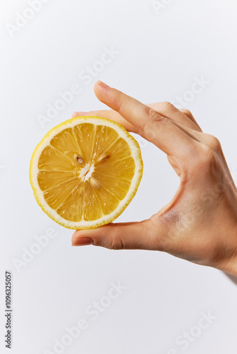 Person holding half of a lemon on a white background with the other half on the other side of their hand photo