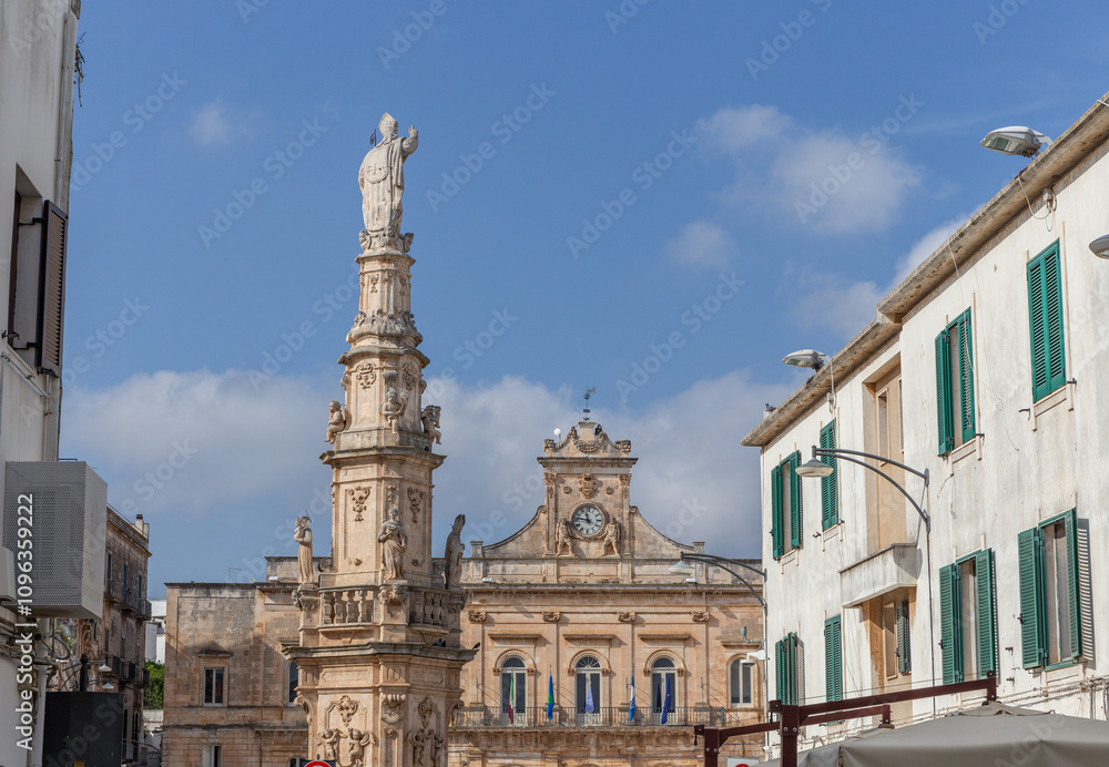 Obraz premium Colonna di Sant'Oronzo in Ostuni, Apulien, Italien. Ein 20 Meter hoher Obelisk, der dem Schutzpatron der Stadt, Sant'Oronzo, gewidmet ist. Er befindet sich auf der Piazza della Libertà, wo auch das R