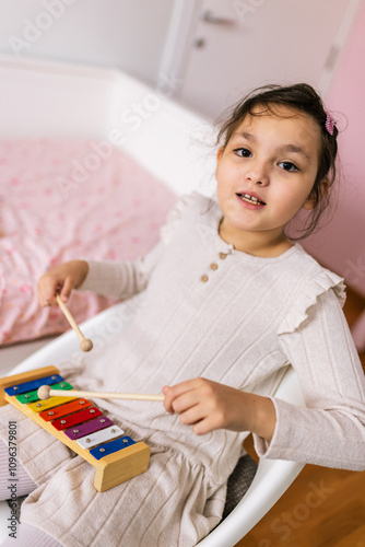 Girl with autism plays metallophone. Music therapy at home photo