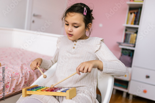 Girl with autism plays metallophone. Music therapy at home photo