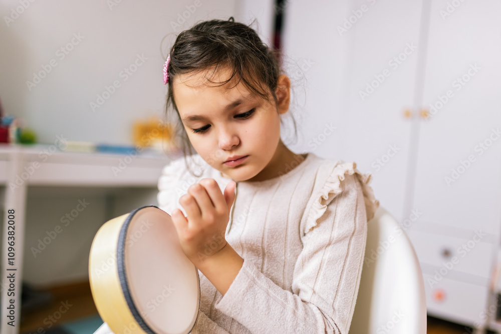 Little girl with autism plays percussion instrument. Music therapy at home. Little girl with autism plays percussion instrument. Music therapy at home.