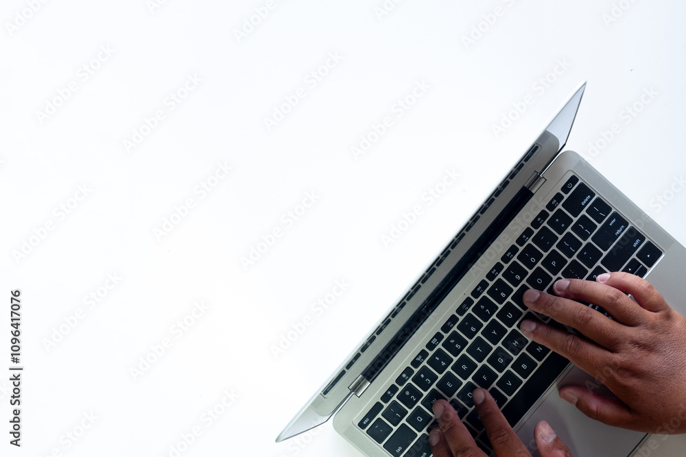 Fototapeta premium Selective Focus Top View of a Hand Typing on a Laptop Over a White Background, Minimalist Technology Concept.