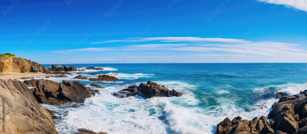 Rugged beach coastline under a clear blue sky with gentle waves crashing on rocky formations near the gulf shoreline Rugged beach coastline under a clear blue sky with gentle waves crashing on rocky formations near the gulf shoreline