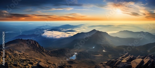 Breathtaking sunrise view from a mountain peak showcasing vast landscapes and dramatic sky with clouds and distant hills.