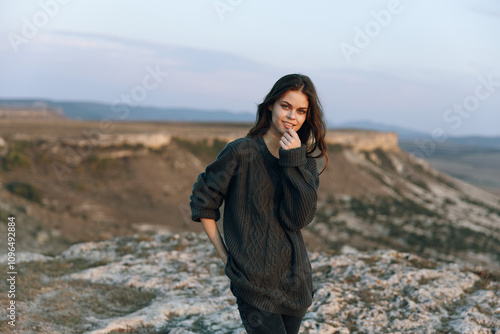 Woman in black sweater standing on hill overlooking majestic mountains in peaceful solitude photo