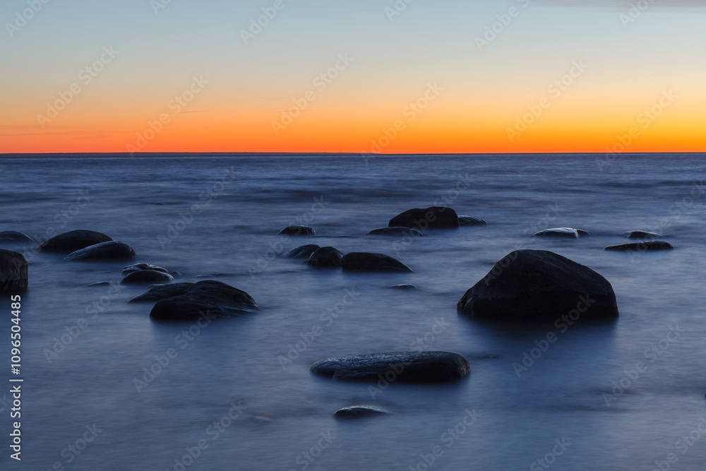 Sunset on the coast of the Baltic Sea. Stones on the shallow sea shore. Sunset on the coast of the Baltic Sea. Stones on the shallow sea shore.