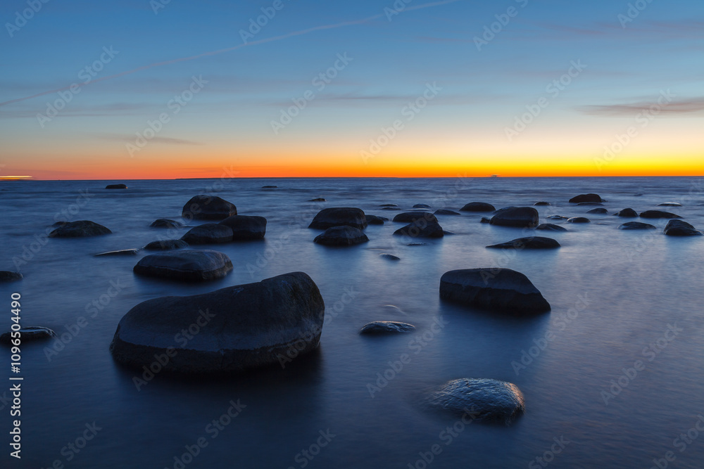 Sunset on the coast of the Baltic Sea. Stones on the shallow sea shore. Sunset on the coast of the Baltic Sea. Stones on the shallow sea shore.