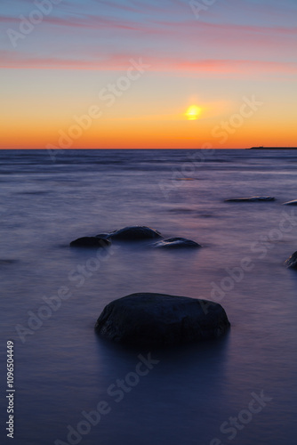 Sunset on the coast of the Baltic Sea. Stones on the shallow sea shore. photo