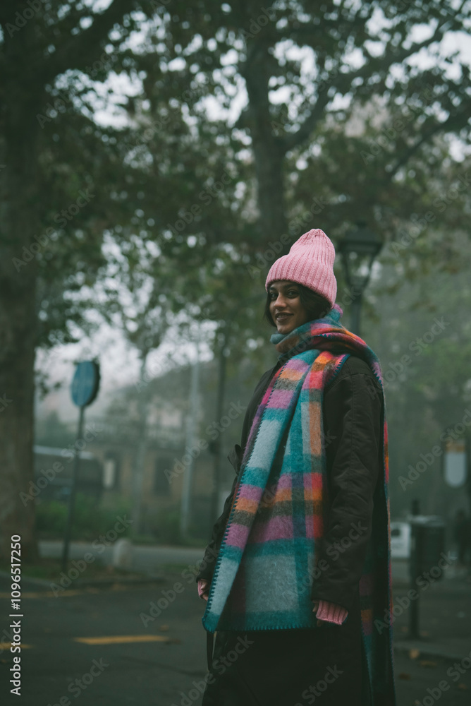 A woman in a pink hat and colorful scarf is on the street A woman in a pink hat and colorful scarf is on the street