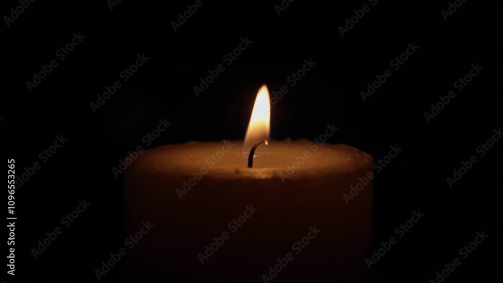 A solitary candle burns steadily, its flame flickering softly as wax melts and drips, casting a warm glow against a deep black background. A solitary candle burns steadily, its flame flickering softly as wax melts and drips, casting a warm glow against a deep black background.