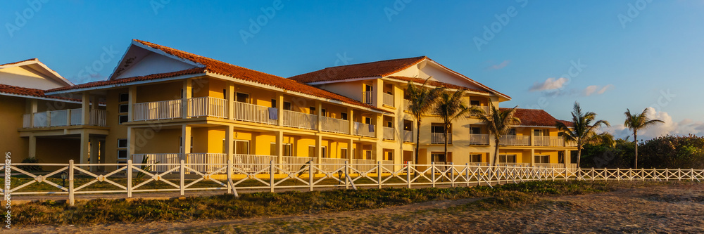 A hotel with a white fence and a red roof A hotel with a white fence and a red roof
