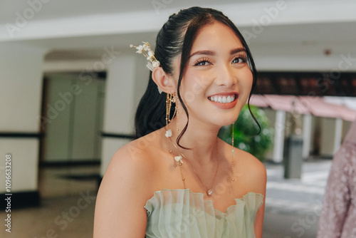 Happy young Asian woman wearing a green dress is showing a smiling expression to the camera. Free Download Happy young Asian woman wearing a green dress is showing a smiling expression to the camera. - GFXLoad