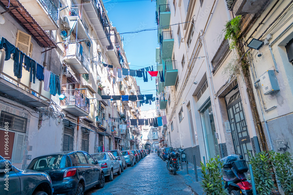 Typical streets in Napoli downtown or old city. Narrow streets with high buildings, clothes hanging on lines and drying bwtween the buildings. Moto scooters everywhere