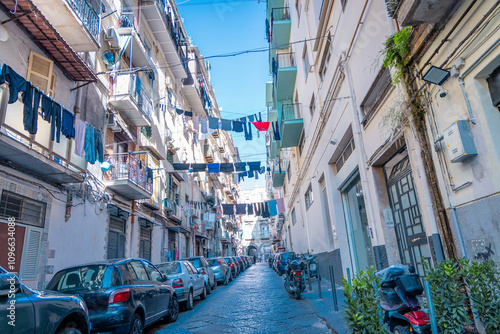 Typical streets in Napoli downtown or old city. Narrow streets with high buildings, clothes hanging on lines and drying bwtween the buildings. Moto scooters everywhere
