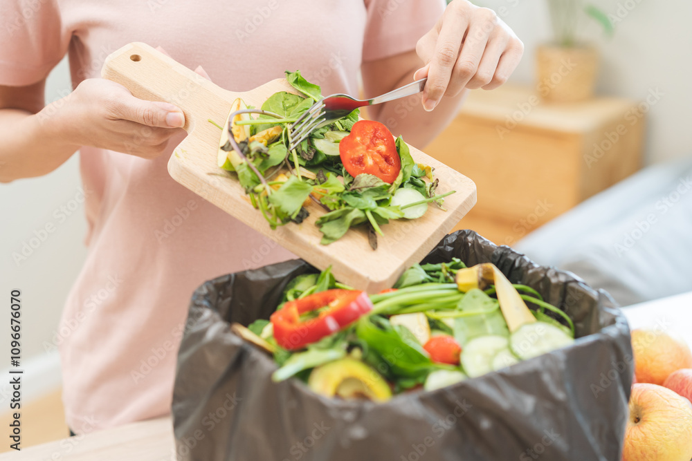 Compost from leftover food, asian young housekeeper woman hand holding cutting board use fork scraping waste, rotten vegetable throwing away into garbage, trash or bin. Environmentally responsible. Compost from leftover food, asian young housekeeper woman hand holding cutting board use fork scraping waste, rotten vegetable throwing away into garbage, trash or bin. Environmentally responsible.