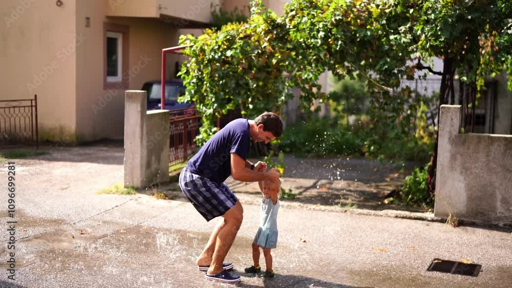 Dad and little daughter are jumping in a puddle holding hands raising splashes. High quality 4k footage Dad and little daughter are jumping in a puddle holding hands raising splashes. High quality 4k footage
