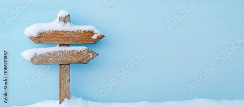 Wooden snow-covered direction sign against a blue background with two arrows pointing in the same direction for navigation themes photo