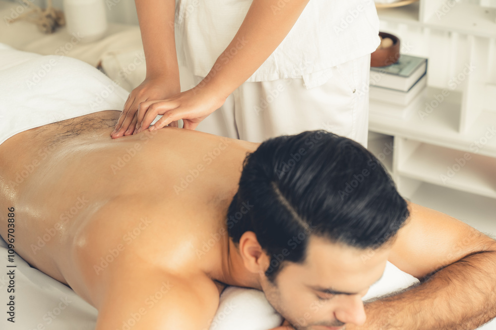 Caucasian man customer enjoying relaxing anti-stress spa massage and pampering with beauty skin recreation leisure in day light ambient salon spa at luxury resort or hotel. Quiescent Caucasian man customer enjoying relaxing anti-stress spa massage and pampering with beauty skin recreation leisure in day light ambient salon spa at luxury resort or hotel. Quiescent