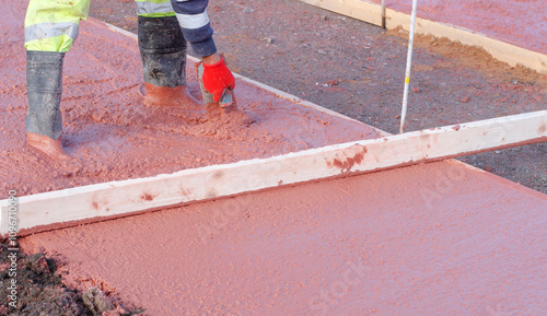 Photography Builder spreads fresh concrete on a construction site during daylight hours in a