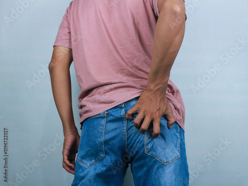 Man in jeans scratching hand his itchy ass