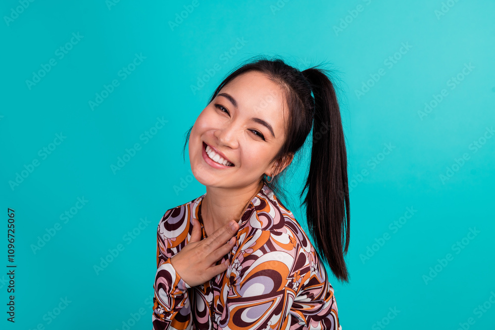 Photo portrait of attractive young woman touch chest cheerful smile dressed stylish colorful clothes isolated on cyan color background Photo portrait of attractive young woman touch chest cheerful smile dressed stylish colorful clothes isolated on cyan color background