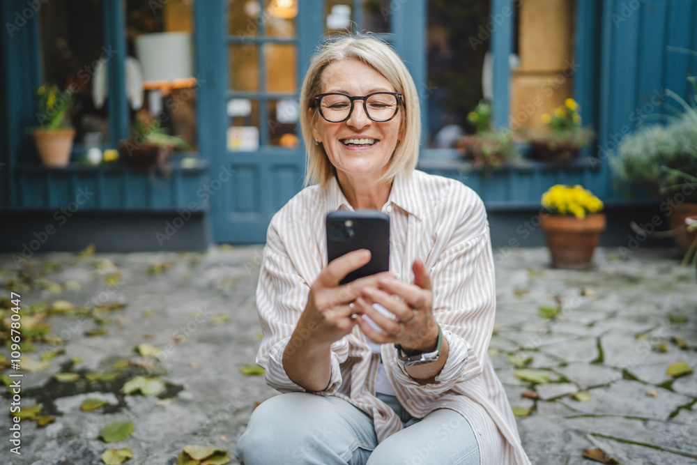 smile mature woman owner sit in front restaurant and use mobile phone smile mature woman owner sit in front restaurant and use mobile phone