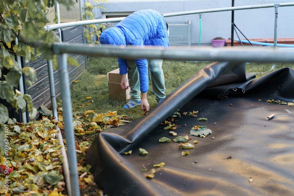 Fototapeta premium Children take apart a large trampoline at home and reassemble it.